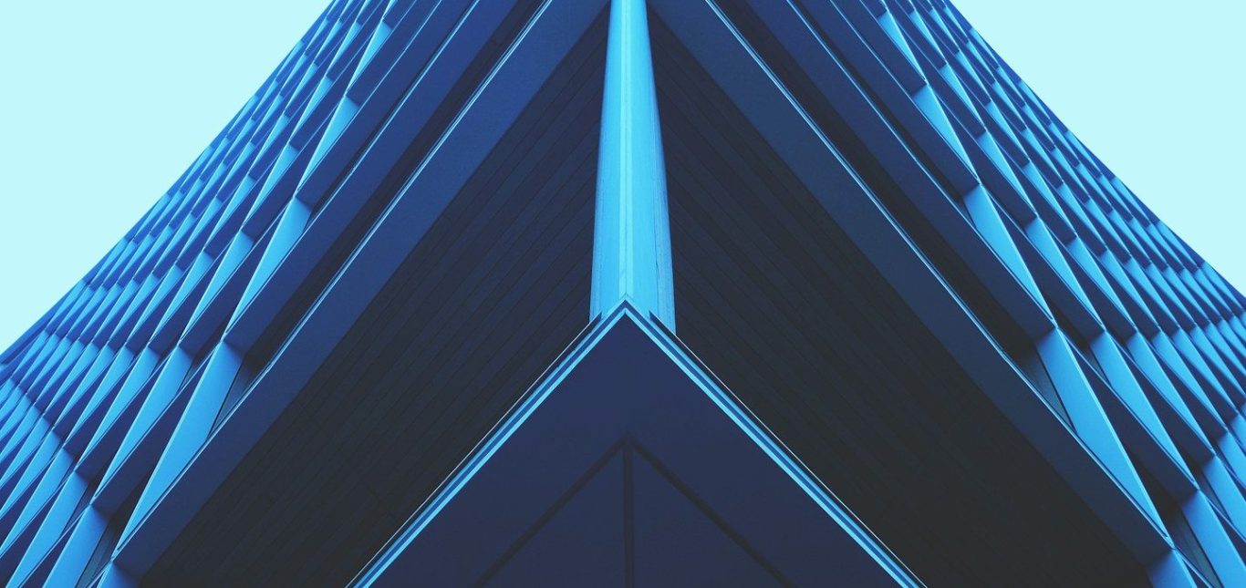 SYNING - SYNTHESE ARCHITECTURALE Vue en plongée d'un bâtiment moderne aux lignes géométriques et aux couleurs bleues.