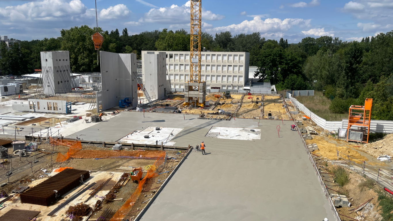 SYNING - CONSEILS INGENIERIE Chantier de construction avec murs en béton, grue et surfaces en béton fraîchement coulées.